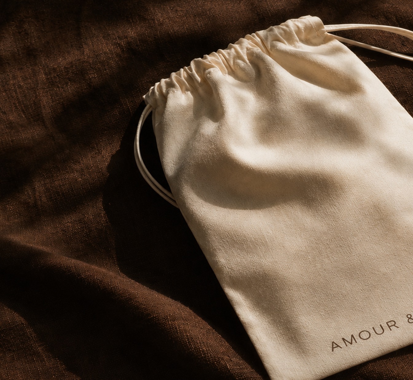 Amour & Mer packaging pouch photographed on fabric